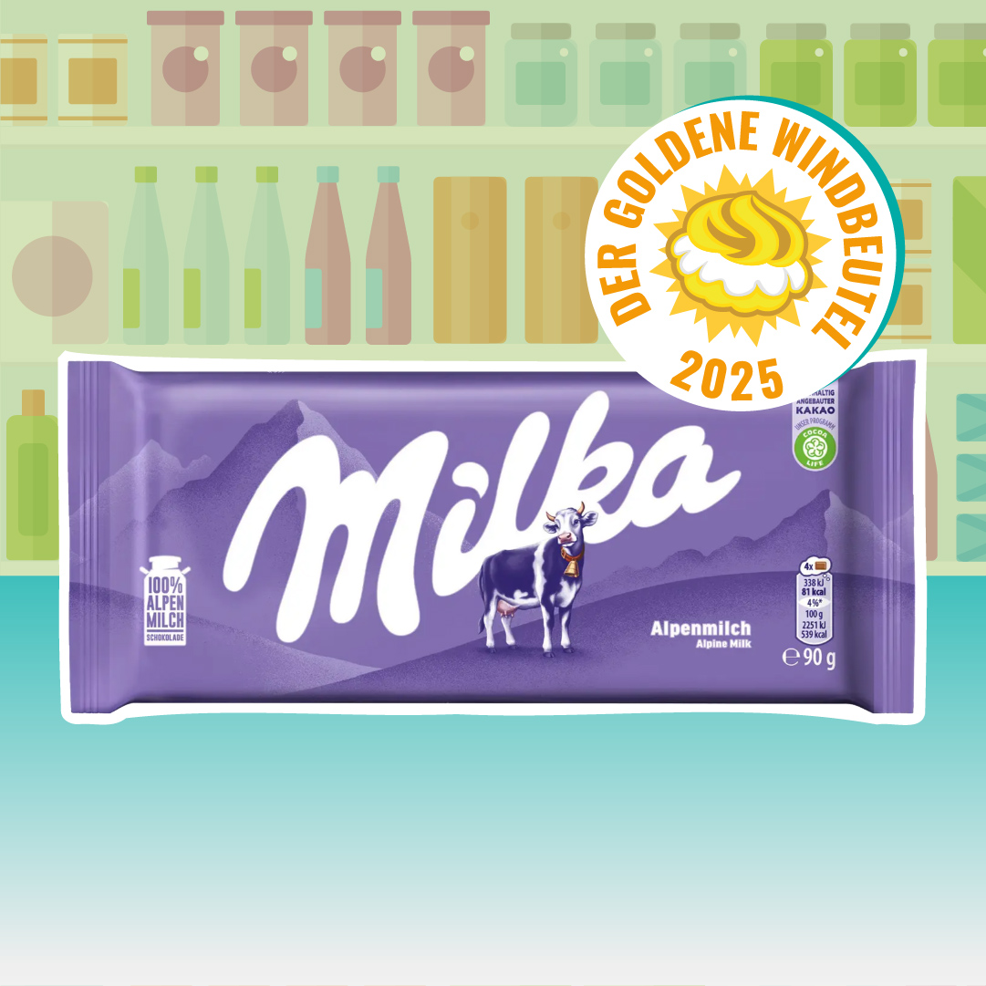 Lila Tafel „Milka Alpenmilch“ mit großem weißem Logo, Alpen-Silhouette und lila Kuh; rechts oben darüber das Siegel „Der Goldene Windbeutel 2025“. Hintergrund: stilisierte Regale.