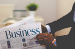 Ein Mann liest eine Zeitung mit der Überschrift „Business“. Foto: Olu Eletu/unsplash