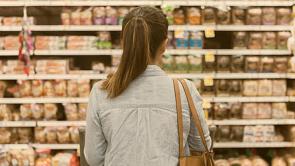 Frau steht vor Supermarkt-Regal
