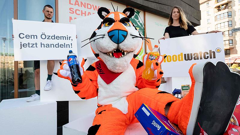 Aktivist:innen mit und ohne Tigerkostüm halten Schilder mit ihren Forderungen hoch 