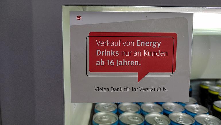 Zettel mit Hinweis auf Altersbeschränkung ab 16 Jahre auf einem Kühlregal mit Energydrinks