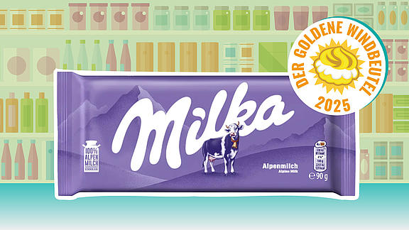 Lila Tafel „Milka Alpenmilch“ mit großem weißem Logo, Alpen-Silhouette und lila Kuh; rechts oben darüber das Siegel „Der Goldene Windbeutel 2025“. Hintergrund: stilisierte Regale.